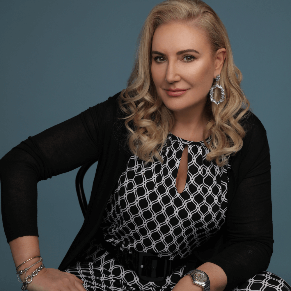 A woman sitting strong wearing rhinestones statement earrings on a blue green background. FIND YOUR CONFIDENCE PIECE: THE BELLE de SOIREE STYLE QUIZ