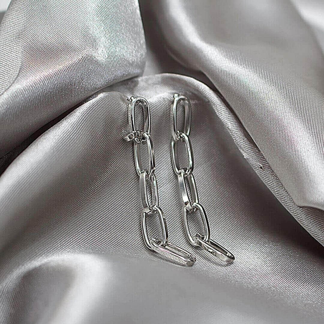 Silver Drop Chain Earrings shown on a luxurious silk material- BELLE DE SOIREE GOLD PLATED DROP EARRINGS