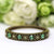 Brass bracelet with green gemstones on a white surface with blurred green flowers in the background