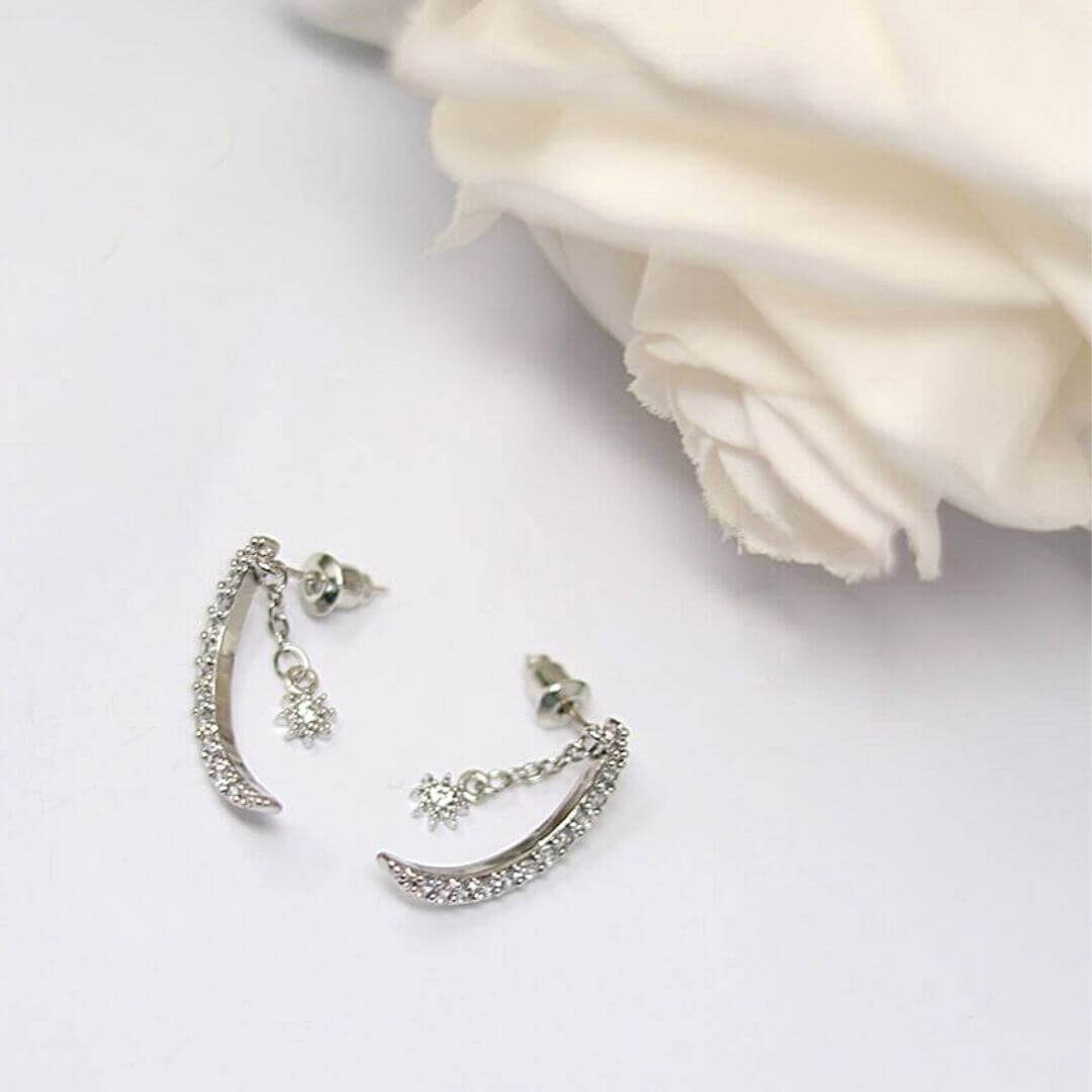 silver earrings on a white background and a flower