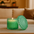 Green candle with decorative lid on a table in a cozy living room setting