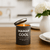 Candle labeled 'Maman Cool' on a wooden table with a blurred background