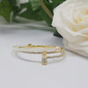 Gold plated Pearl Bangle Riviera is worn by a woman getting ready and looking at her bracelet-belle de soiree riviera