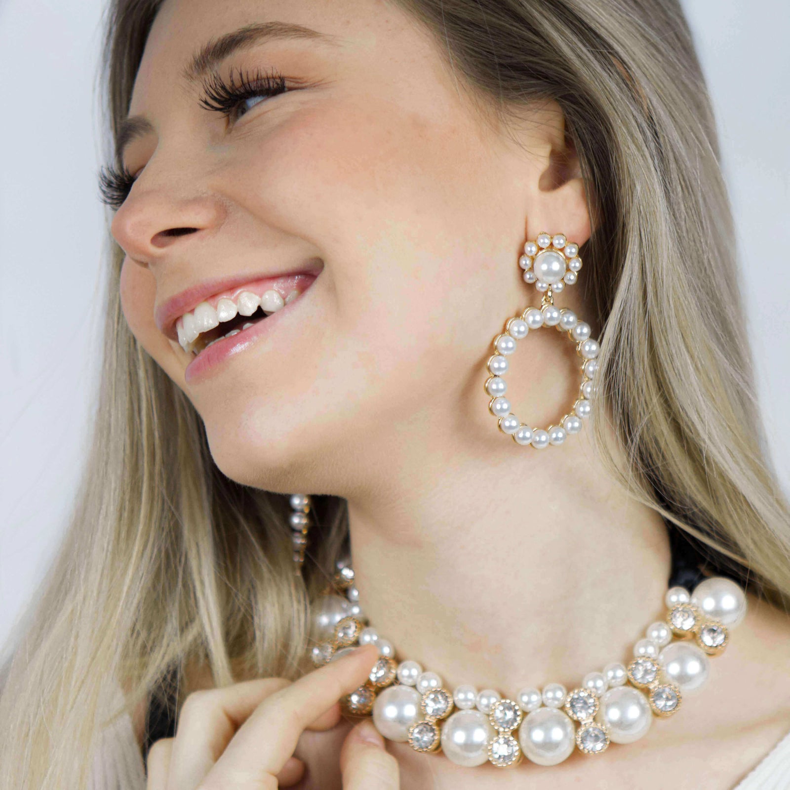 A woman wearing a white pearl necklace, a matching bracelet, and crystal earrings- Belle de Soiree Pearl jewellery set