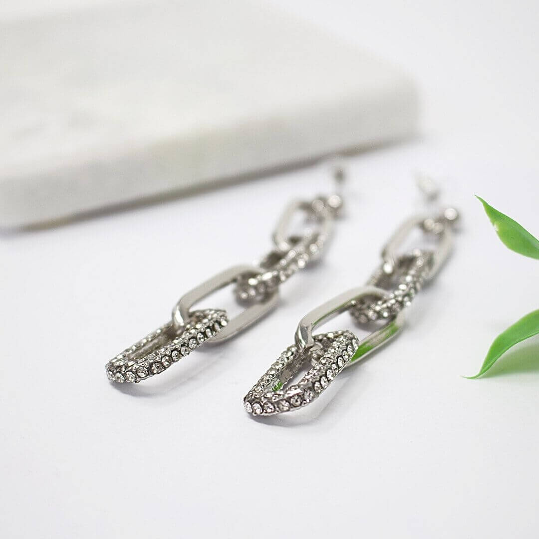 Dazzling Rhinestone Link Earrings shown flat on a white background and green leaves- BELLEDESOIREE