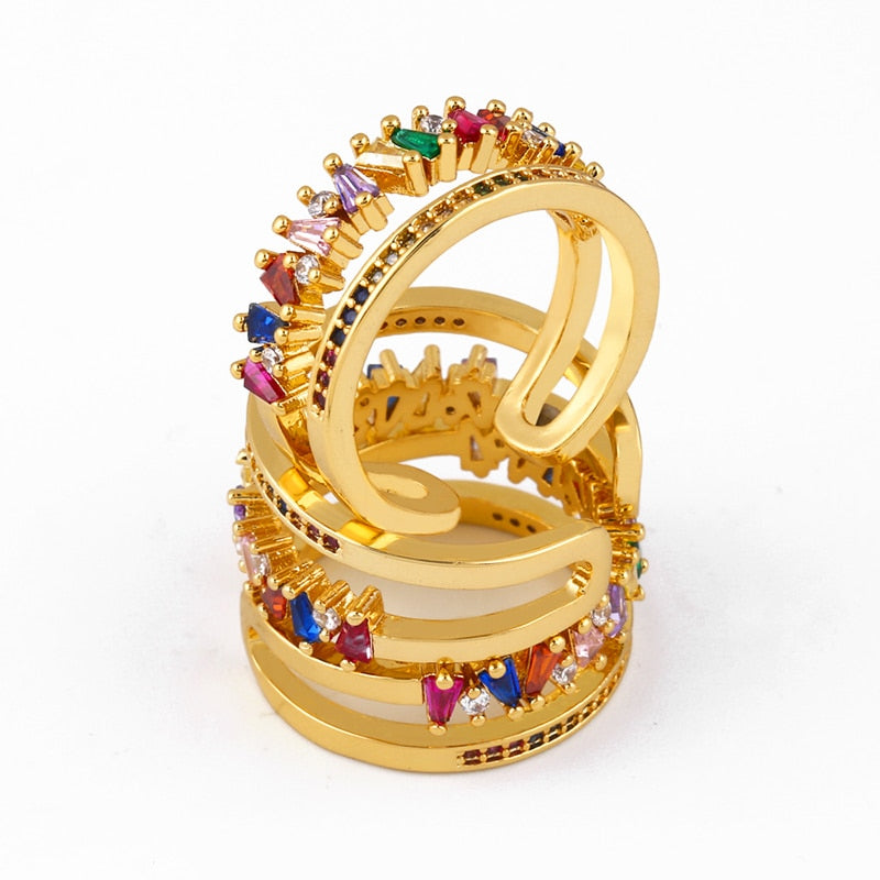 A double ring with a gold-colored band and multicoloured gemstones set in it- belledesoiree