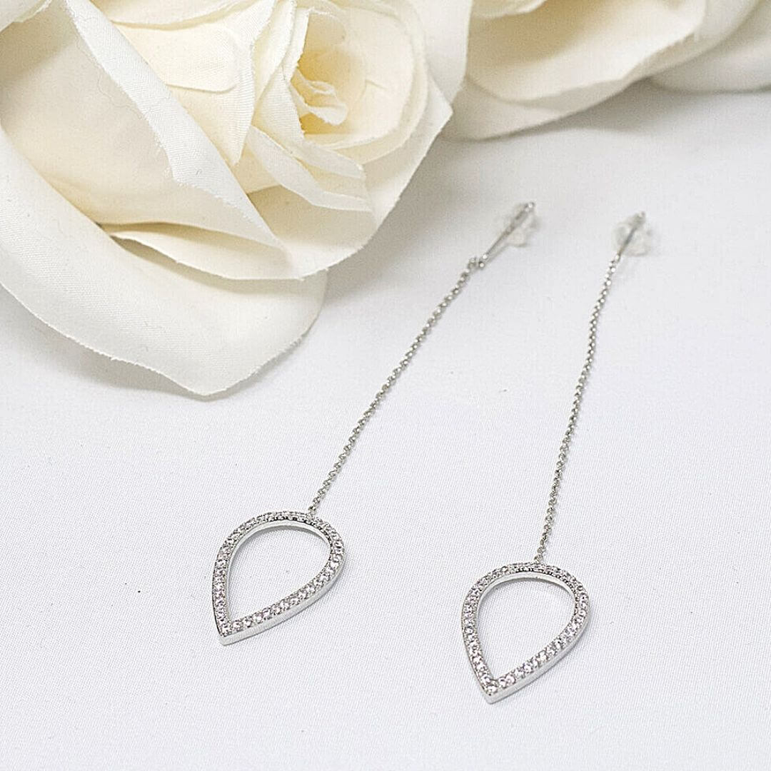 Silver Drop Earrings shown flat in a beautiful background with a flower- BELLE DE SOIREE Silver Drop Earrings