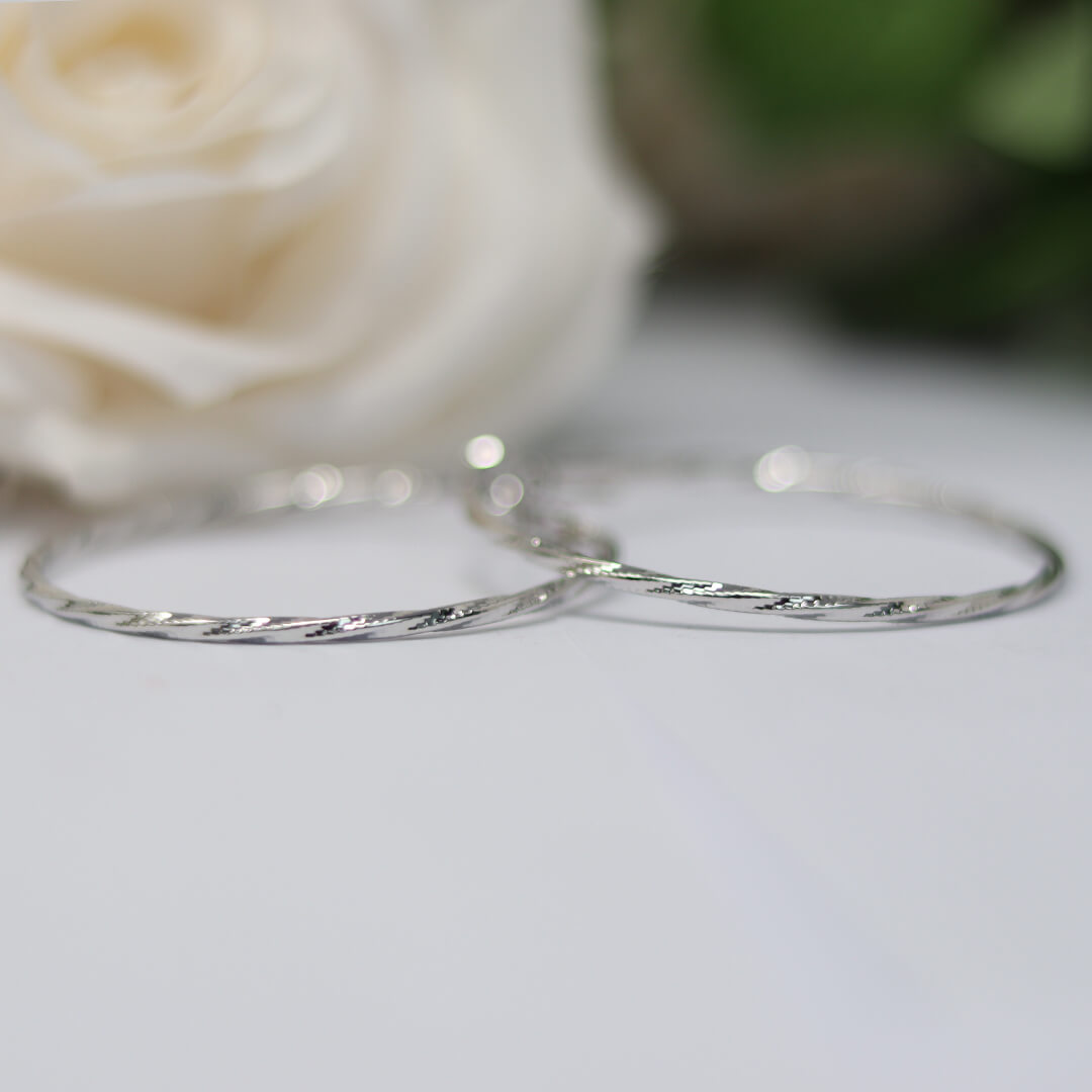The Exciting Crystal Hoop Earrings shown flat on a beautiful grey background with a flower- BELLE DE SOIREE Exciting Crystal Hoop Earrings